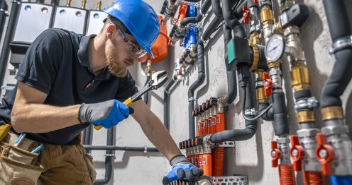 The technician checking the heating system in the boiler room. The technician checking the heating system in the boiler room. Adjusting heating valves in a residential building. A plumbing and heating technician works.