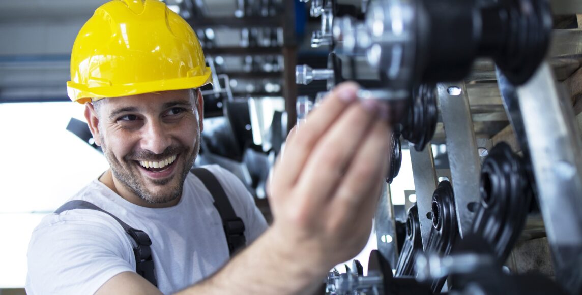 Worker inspecting parts for automobile industry in factory production line.