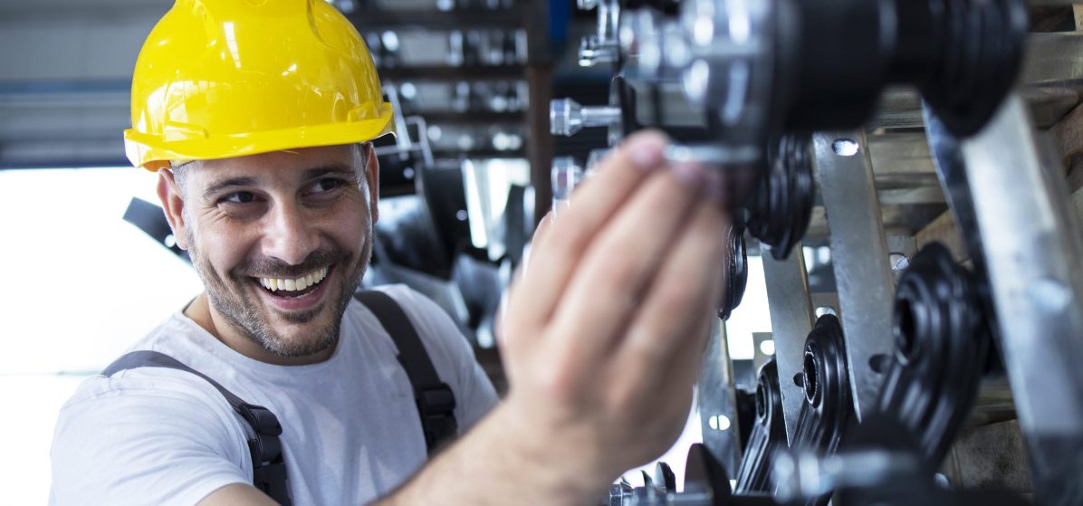 Worker inspecting parts for automobile industry in factory production line.