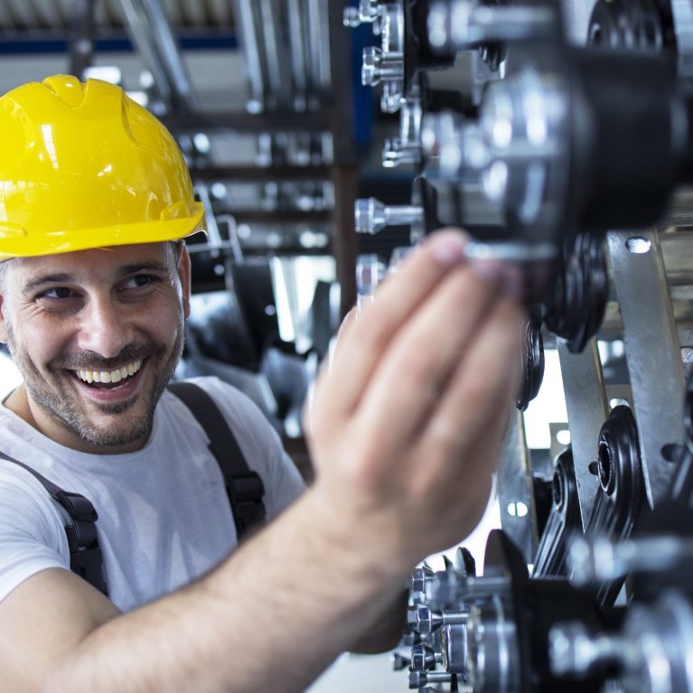 Worker inspecting parts for automobile industry in factory production line.