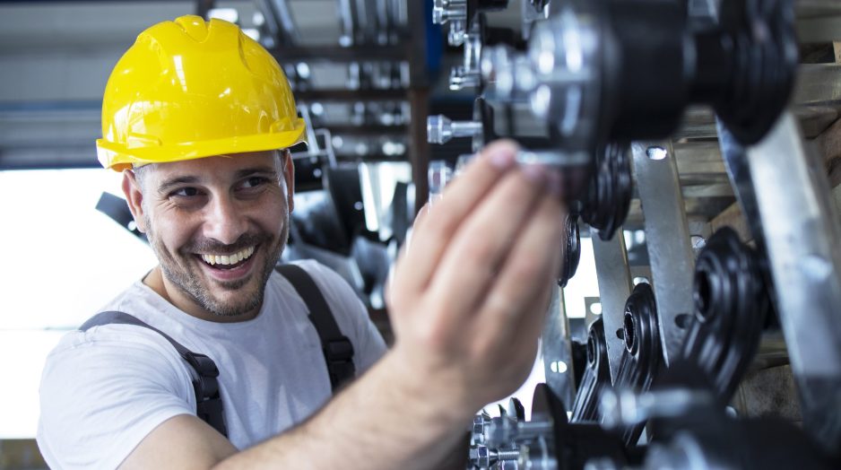 Worker inspecting parts for automobile industry in factory production line.